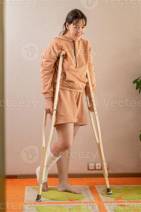 a girl with a broken leg in a cast moves around the apartment on