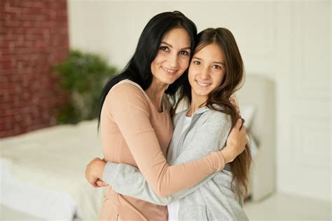 Feliz madre latina e hija abrazándose, sonriendo a la cámara, mirando