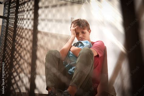 Sad teenage boy sitting on stairs. Bullying at school Stock Photo ...