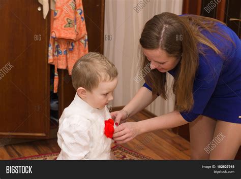 Мать одевает сына