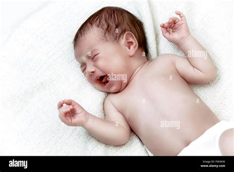 Newborn baby crying in white bad Stock Photo - Alamy