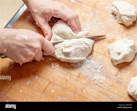 female hands cut   knife  kneaded dough   wooden table stock