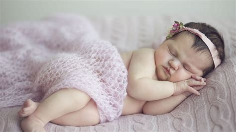cute baby girl is sleeping on bed covered with netted cloth and having ...
