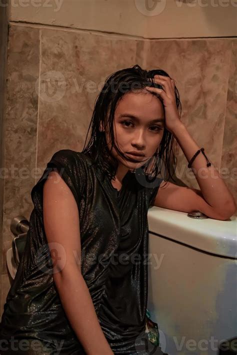 Hot and wet Asian girl poses with sensual style while wearing black wet