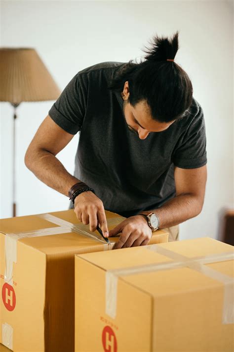 Focused man unpacking carton box in room · Free Stock Photo