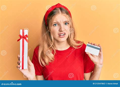 Beautiful Young Caucasian Girl Holding Gift and Credit Card in Shock ...