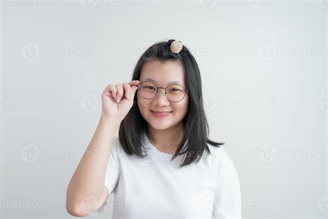 Young Asian glasses girl touches her glasses and smiles to camera on