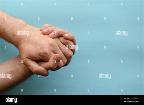 Interlocked fingers of two male hands on blue background. Hands of an ...