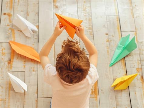 Niño jugando con un avión de papel | Foto Gratis