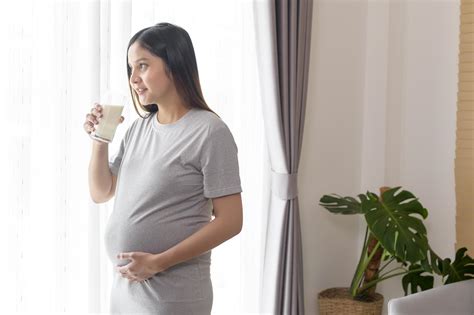 Young pregnant woman drinking milk at home, healthcare and pregnancy