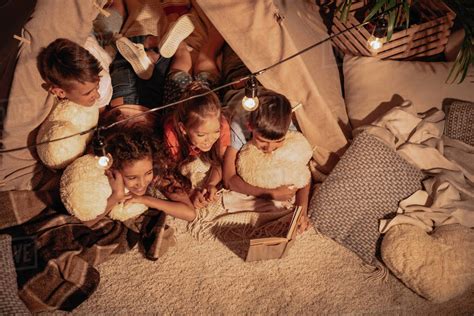 High angle view of multicultural group of children reading book ...