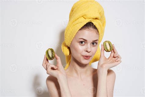 Cheerful woman naked shoulders kiwi in the hands of pure skin natural