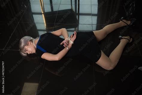Crime scene simulation: dead girl with hands tied lying on the floor