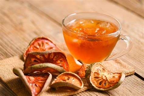 Premium Photo | Bael tea on glass with dried bael slices on wooden ...