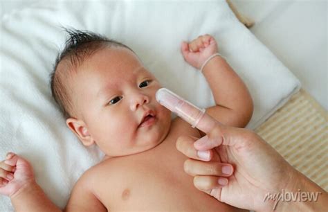 Como Limpar A Lingua Do Bebe - A mãe usa o dedo para limpar a língua e a gengiva do bebê com ...
