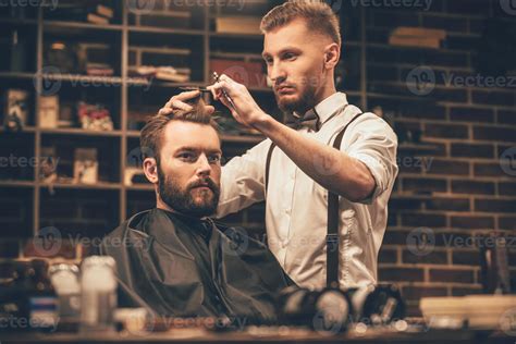 Making haircut look perfect. Young bearded man getting haircut by