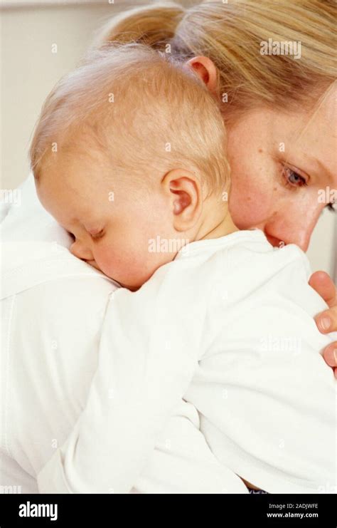 Mother and baby. Mother holding her sleeping 7-month-old baby daughter ...