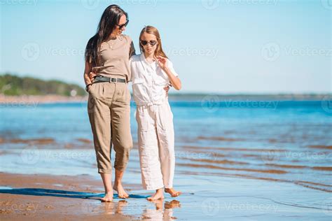 Beautiful mother and daughter at the beach enjoying summer vacation