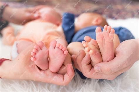 Маленькие ножки новорожденных недоношенных близнецов в руках родителей ...