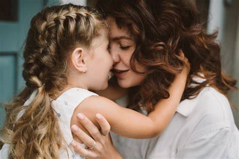 Retrato de pequeña hija besando a su hermosa madre feliz | Foto Gratis