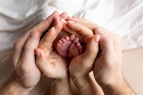 Hände von Eltern und Kindern. Beine eines Neugeborenen in den Händen ...