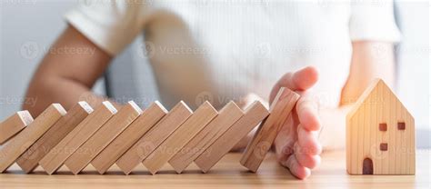 woman hand stop falling wood blocks and protect house model. Crisis