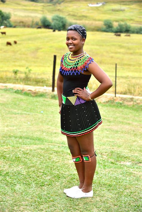 a woman standing on top of a lush green field next to a grass covered field