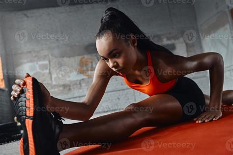 Confident young African woman stretching on splits in gym 10177335