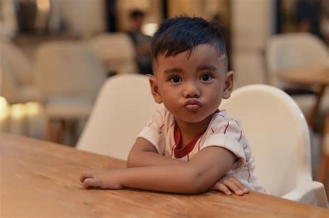 Premium Photo | Smiling young asian boy sitting chair restaurant ...