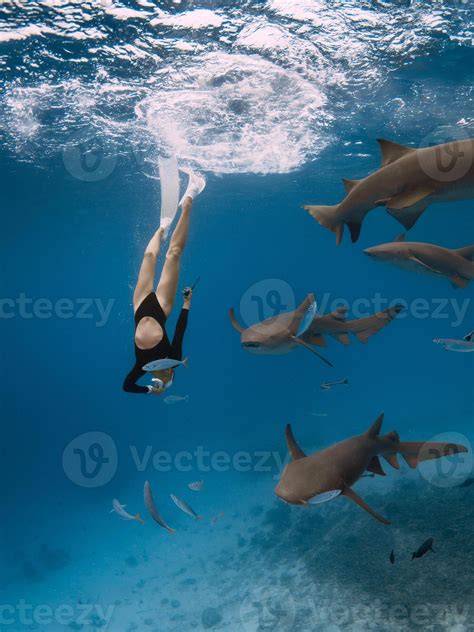 Woman dives with sharks in a tropical sea in the Maldives. Free diving