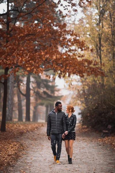Happy interracial couple walking in autumn park, black man and white