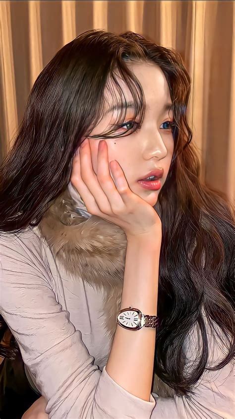 a woman with long dark hair wearing a fur collar and bracelet on her ...