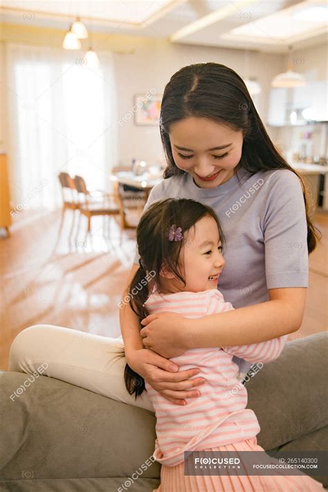 Beautiful happy asian mother and daughter hugging at home — together