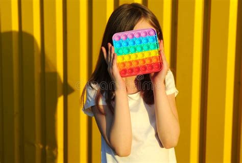 Close Up Portrait of Little Girl Holding a Toy on Her Face on a Yellow ...