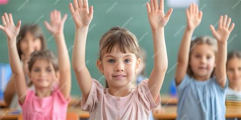 Children raising hands in classroom with Back To School backdrop ...