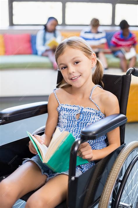 Portrait of disabled school girl reading book in library | Premium Photo