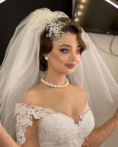 a woman wearing a wedding dress and veil with pearls on her head is ...