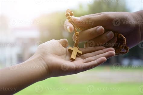 Closeup hands which offering wooden cross bead rosary to other people ...