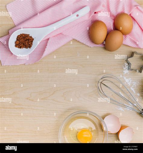 Elevated view chocolate powder eggs egg yolk whisk pastry cutter wooden ...
