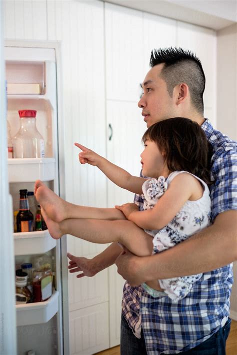 "Little Asian Girl Looking Into A Refrigerator With Her Dad In The