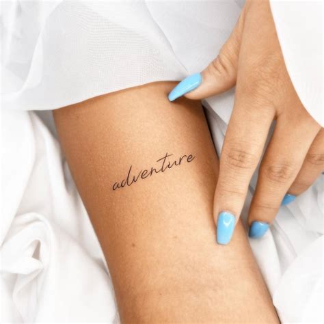 Word "adventure" tattooed on the bicep.