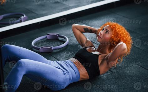 Concentrated at exercise. Sporty redhead girl have fitness day in gym