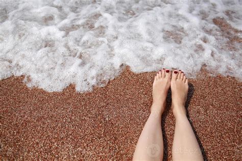Travel concept - Woman's legs on beautiful tropical beach with pebble