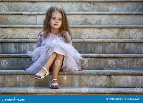 Portrait of a Beautiful Little Girl. the Child is Sitting on the Steps ...