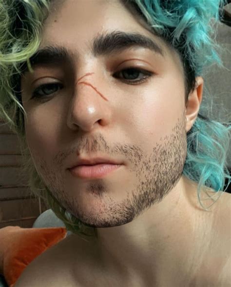 a man with blue and green hair is looking at the camera while wearing a wig