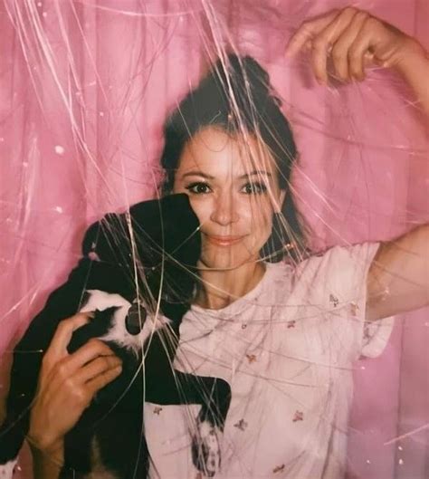 a woman holding a cat in her arms and looking through the hair on top ...