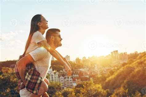 Romantic young couple having fun while man giving his girlfriend piggy