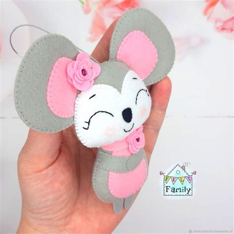 a hand holding a gray and pink mouse with flowers on it's ear,