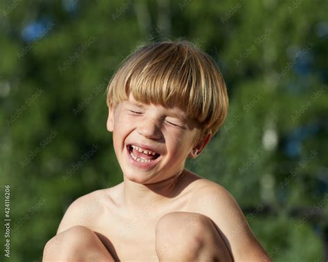 Portrait of naked little boy squatting on haunches with eyes closed and