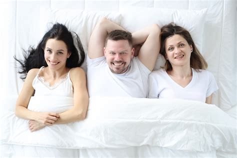 2 Mulheres E Um Homem - Duas mulheres sorridentes e um homem deitados na cama | Foto Premium